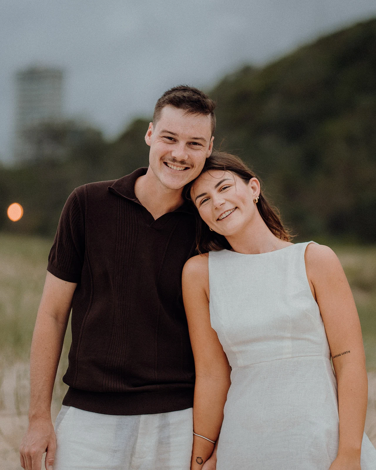 A smiling couple lean their heads together on the beach.
