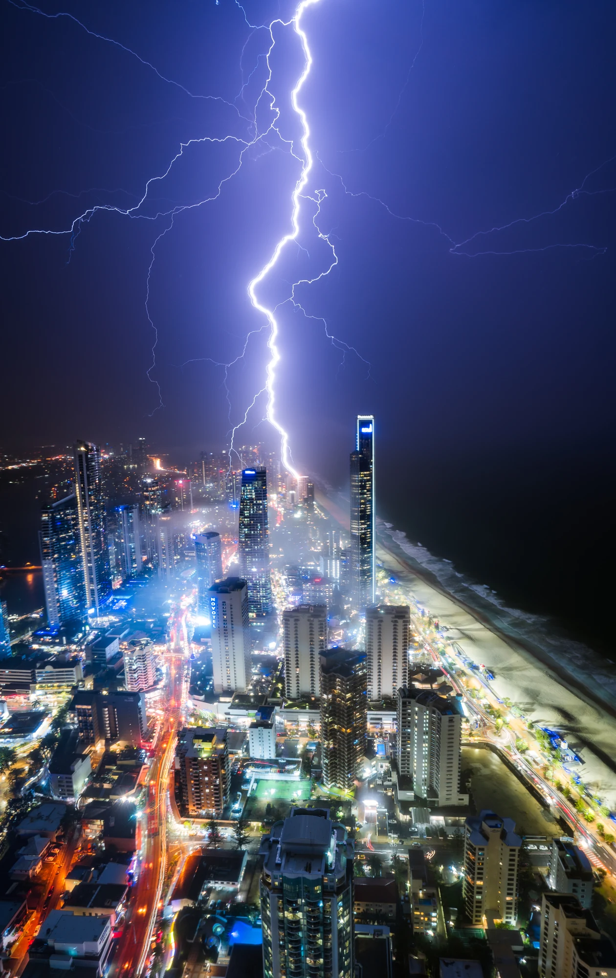 Purple lightning branches above the illuminated Gold Coast skyline at night.