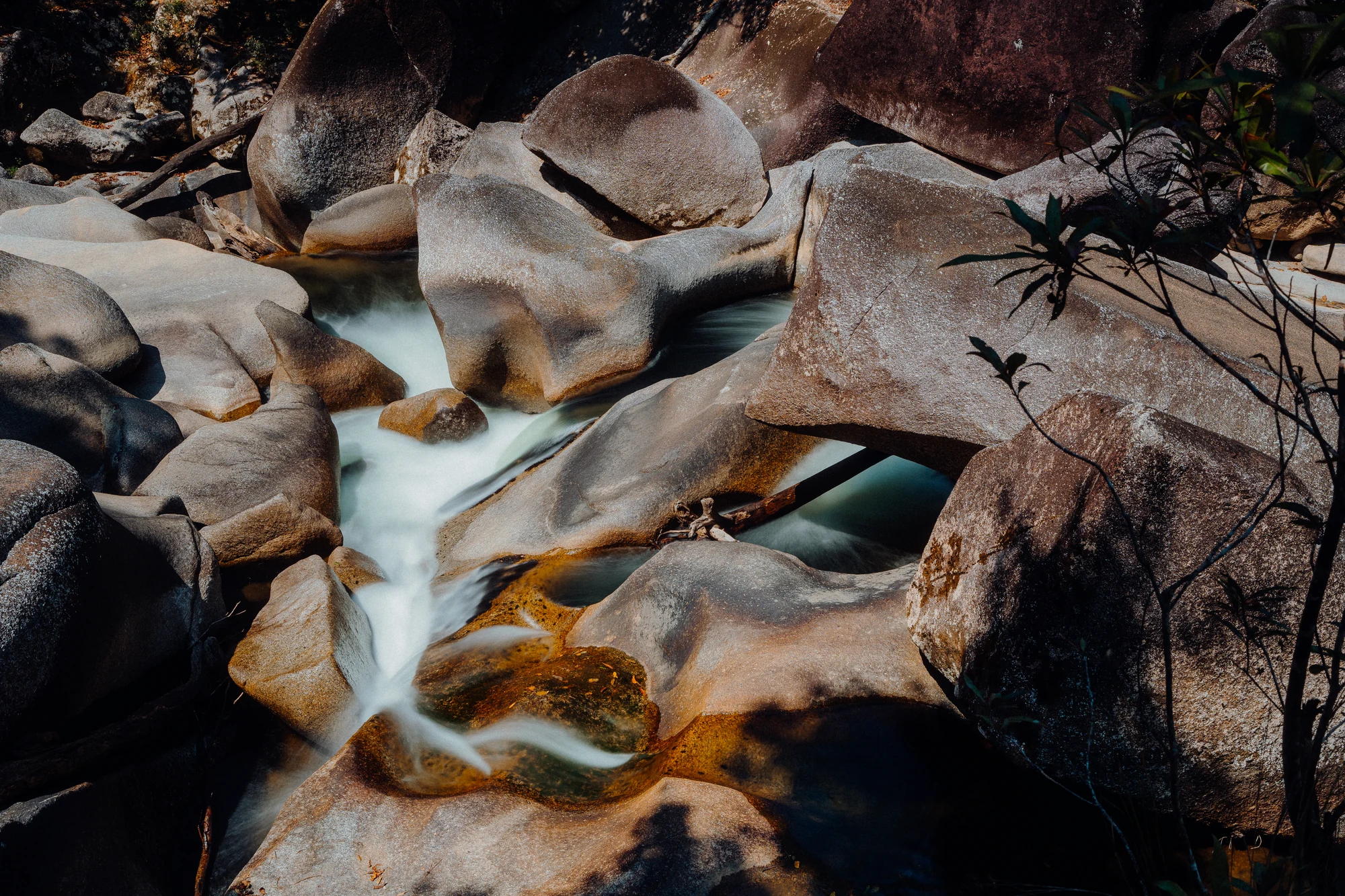 Silky water runs between sculpted hollows in warm granite rocks.