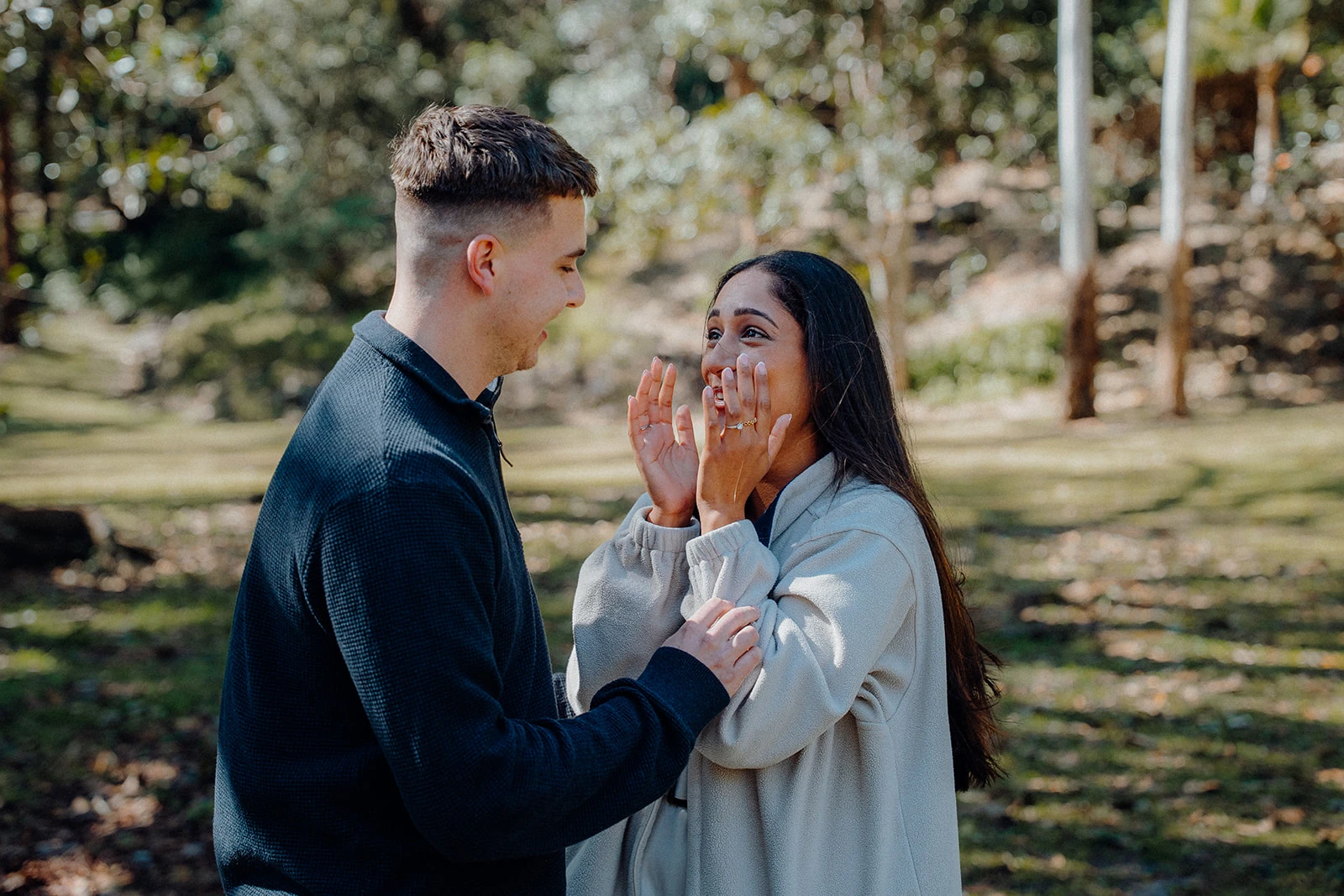 A woman smiles in surprise as her partner holds her arm.