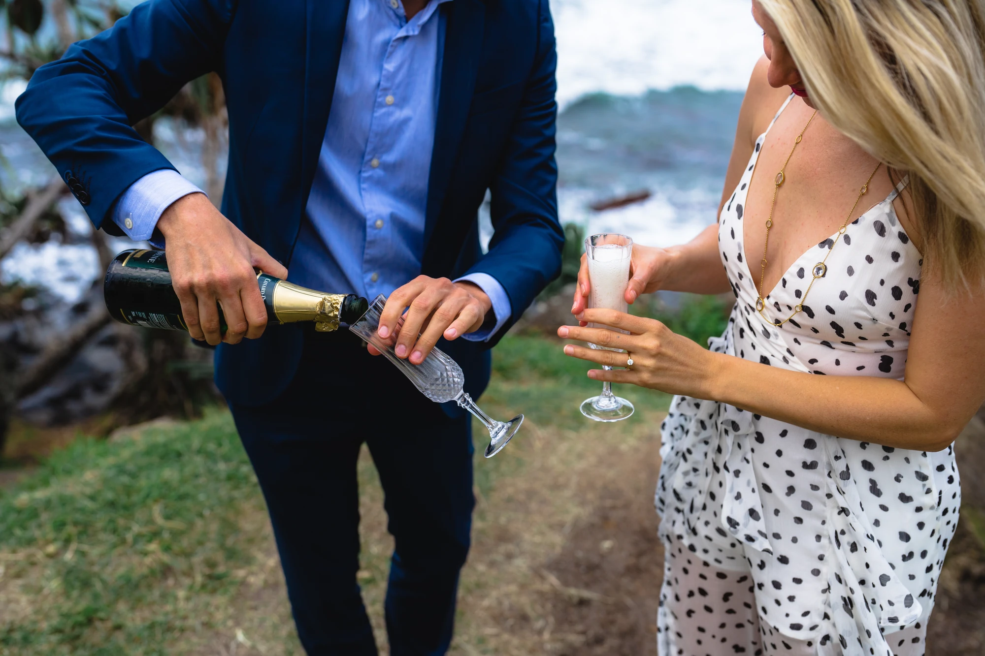 A man pours champagne as his partner holds her glass beside him.