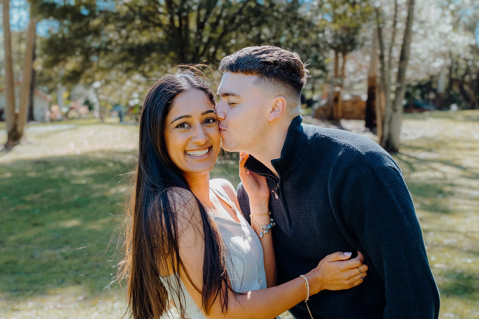 A man kisses his smiling partner on the cheek.