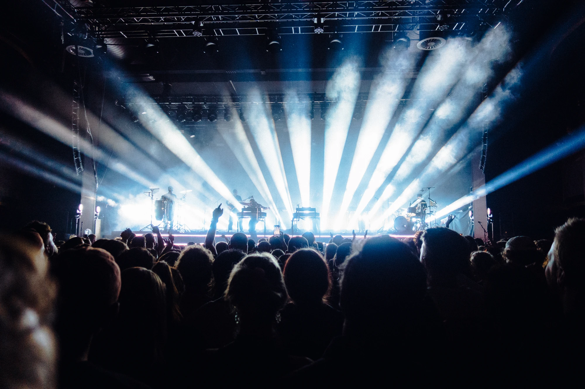 White stage beams fan out over a concert audience.