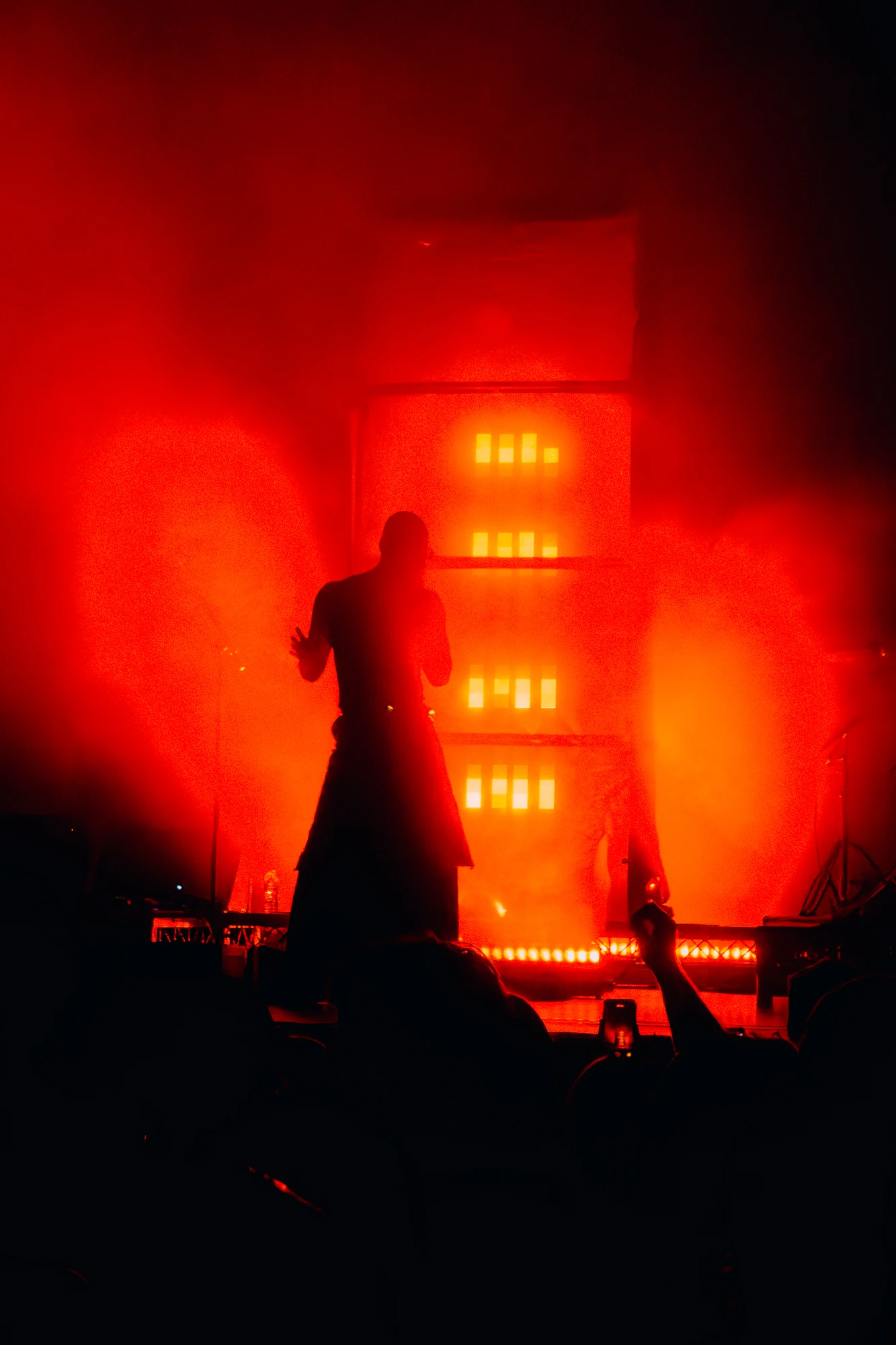 A singer is silhouetted against a column of red light.