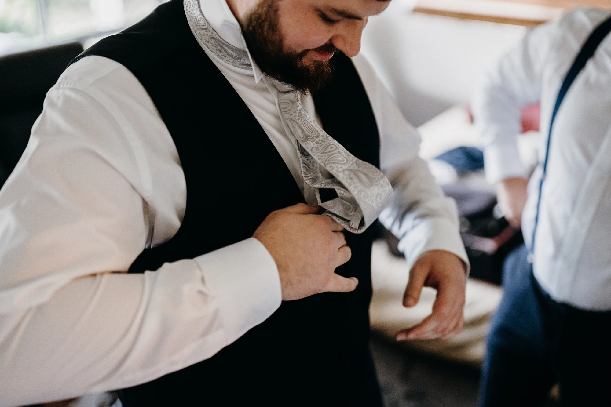 Close view of a groom adjusting his waistcoat and tie.