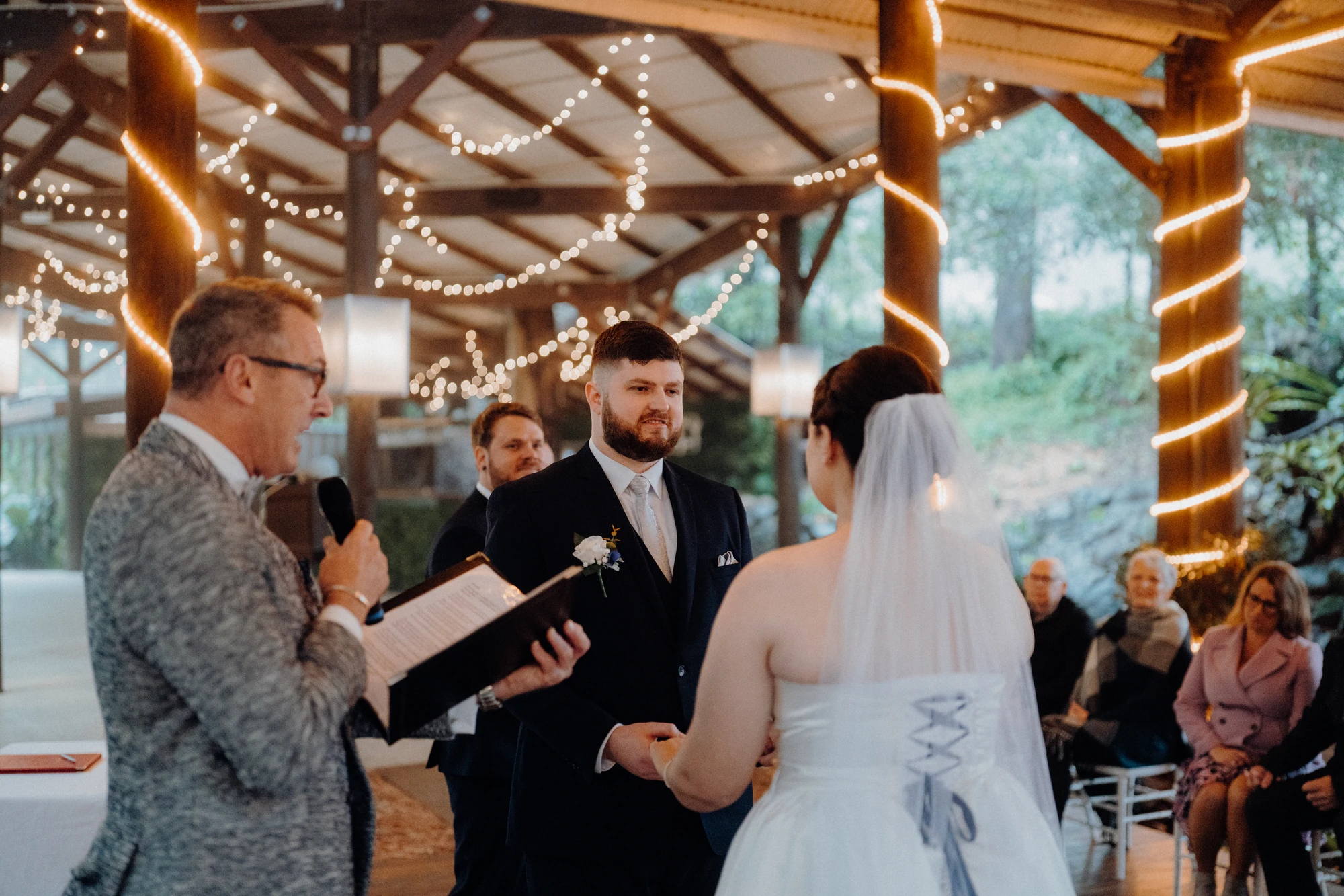 A groom looks at his bride as the celebrant reads beside them.