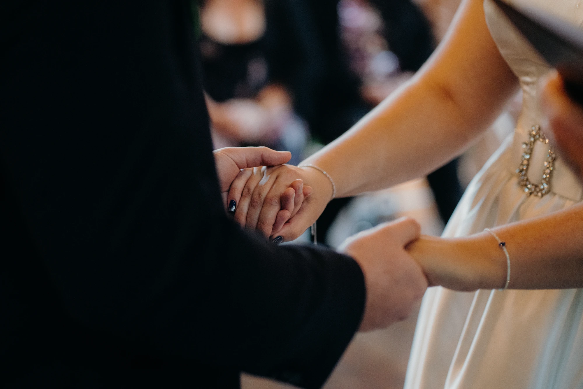 A couple hold hands during their wedding ceremony.