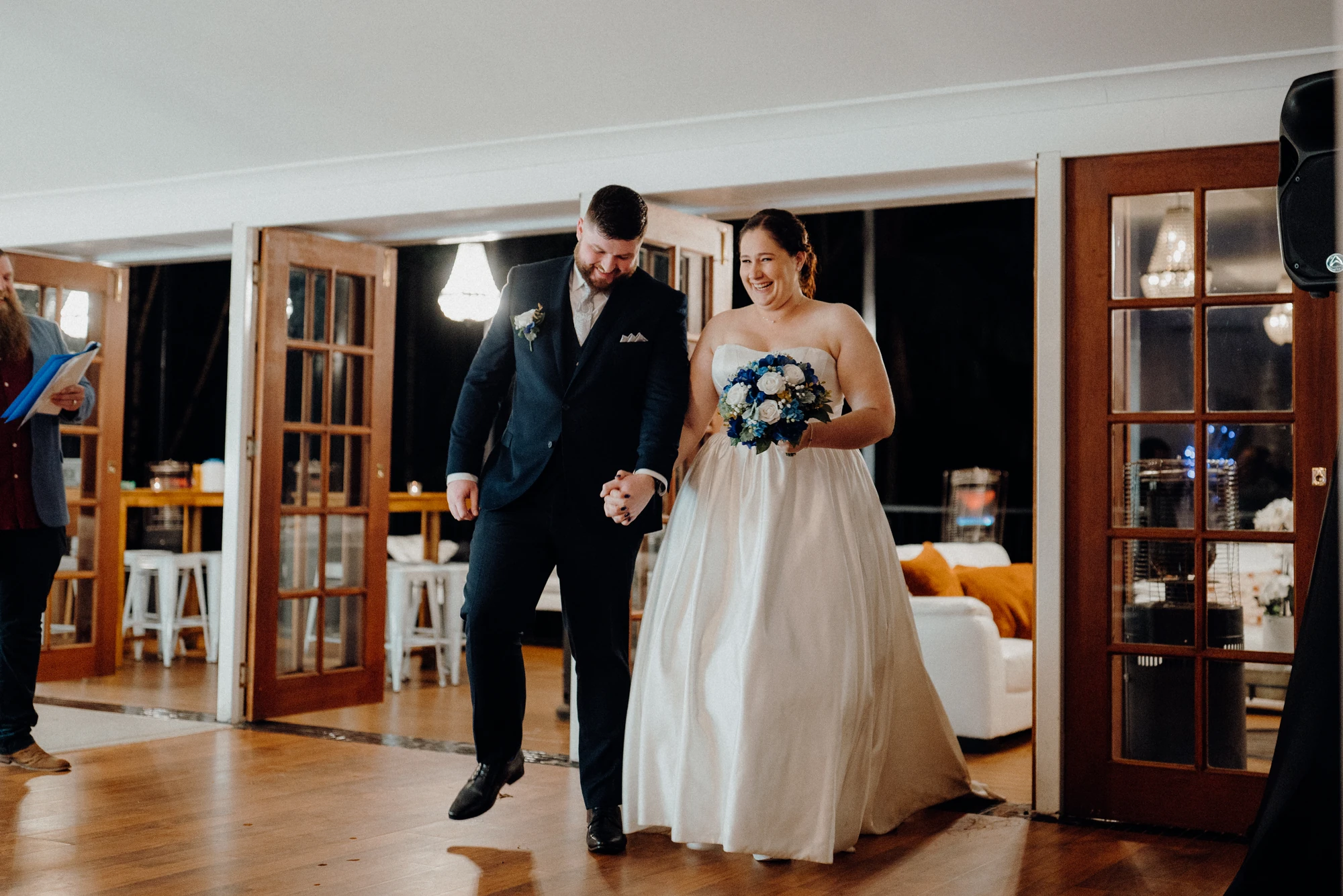 Newlyweds enter their reception holding hands.