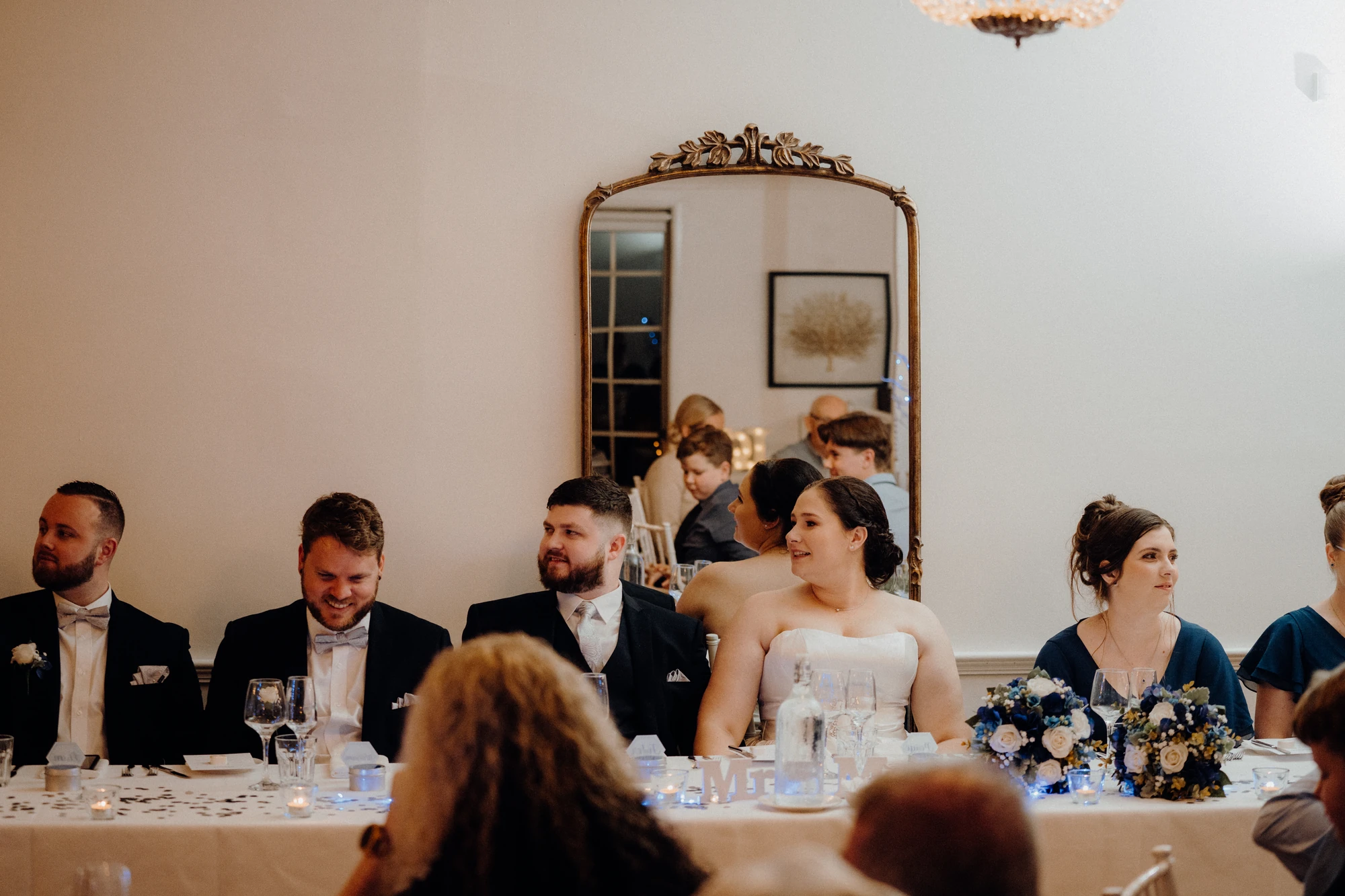 The wedding party listens to a speech at the reception table.