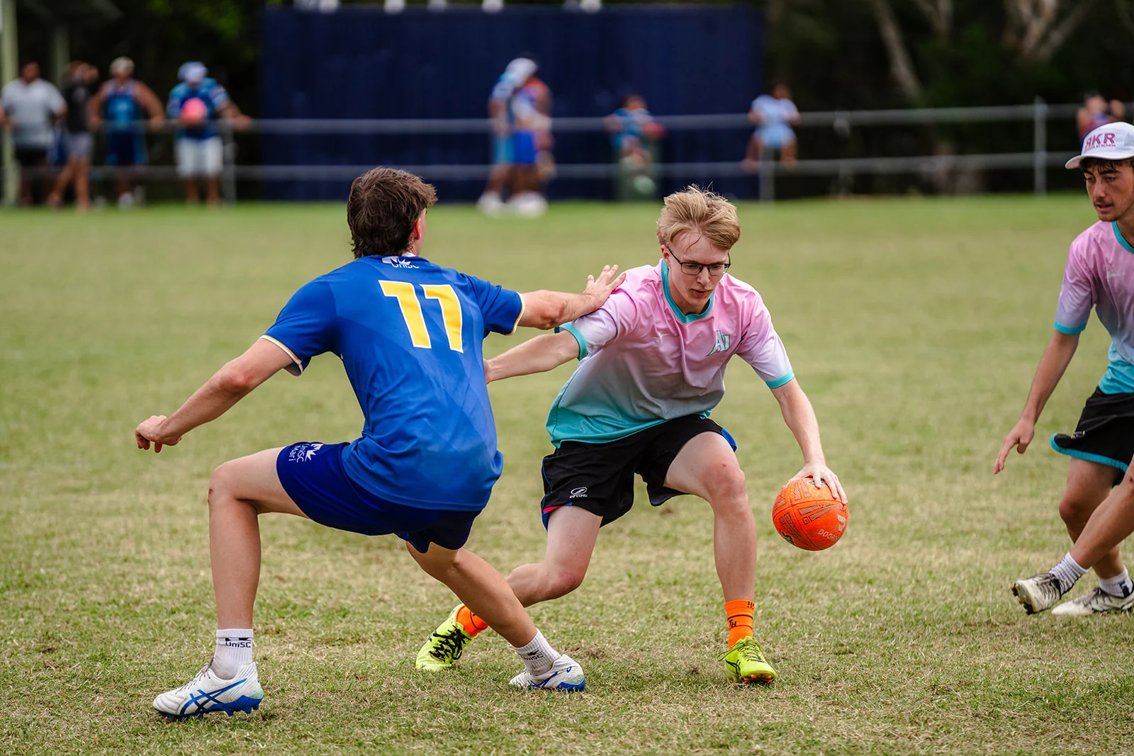 A player with an orange ball changes direction around a crouching defender.