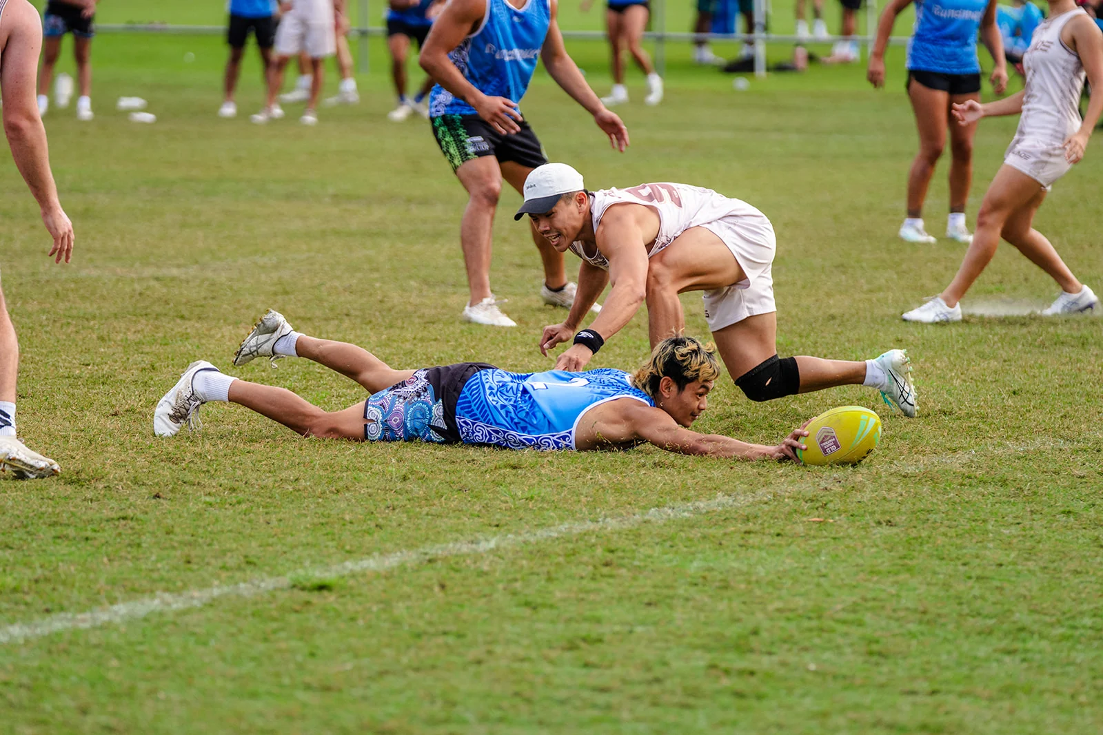 A player in blue stretches toward the line as a defender reaches over him.