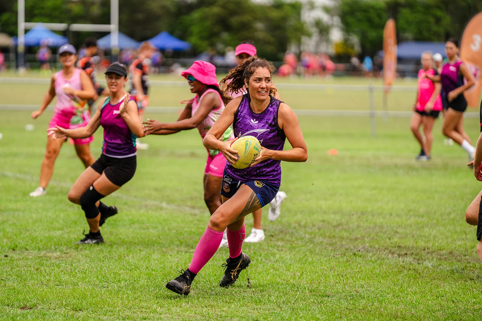 A woman in purple breaks forward with the ball and a smile during play.