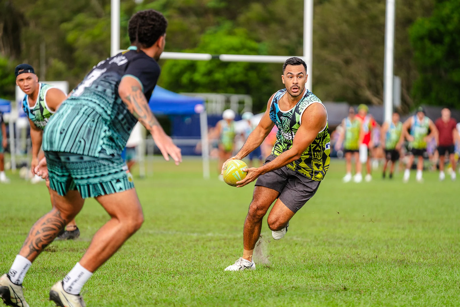 A ball carrier turns with both hands on the ball as a defender closes in.