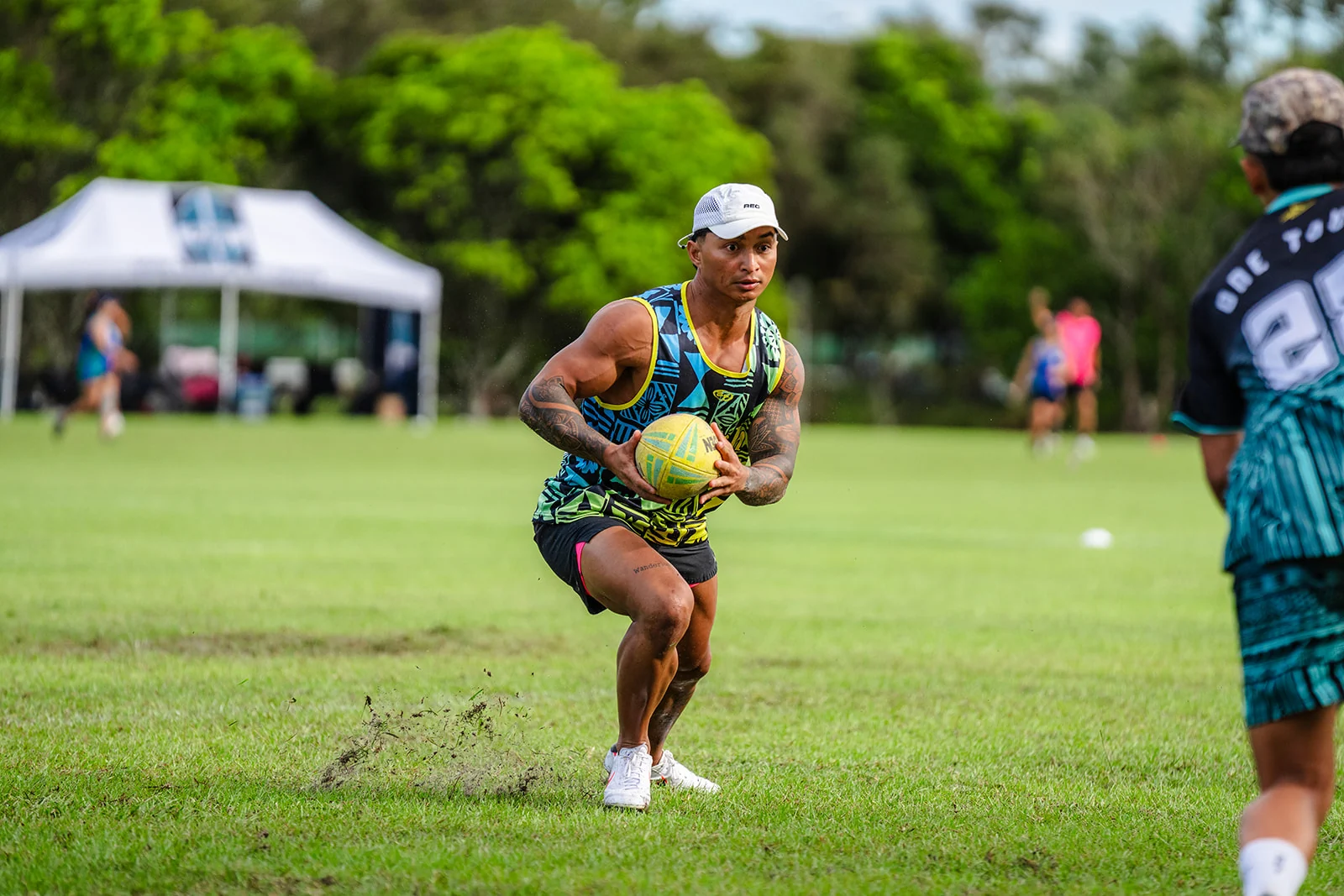 A player in a cap watches a defender while holding the ball at his waist.