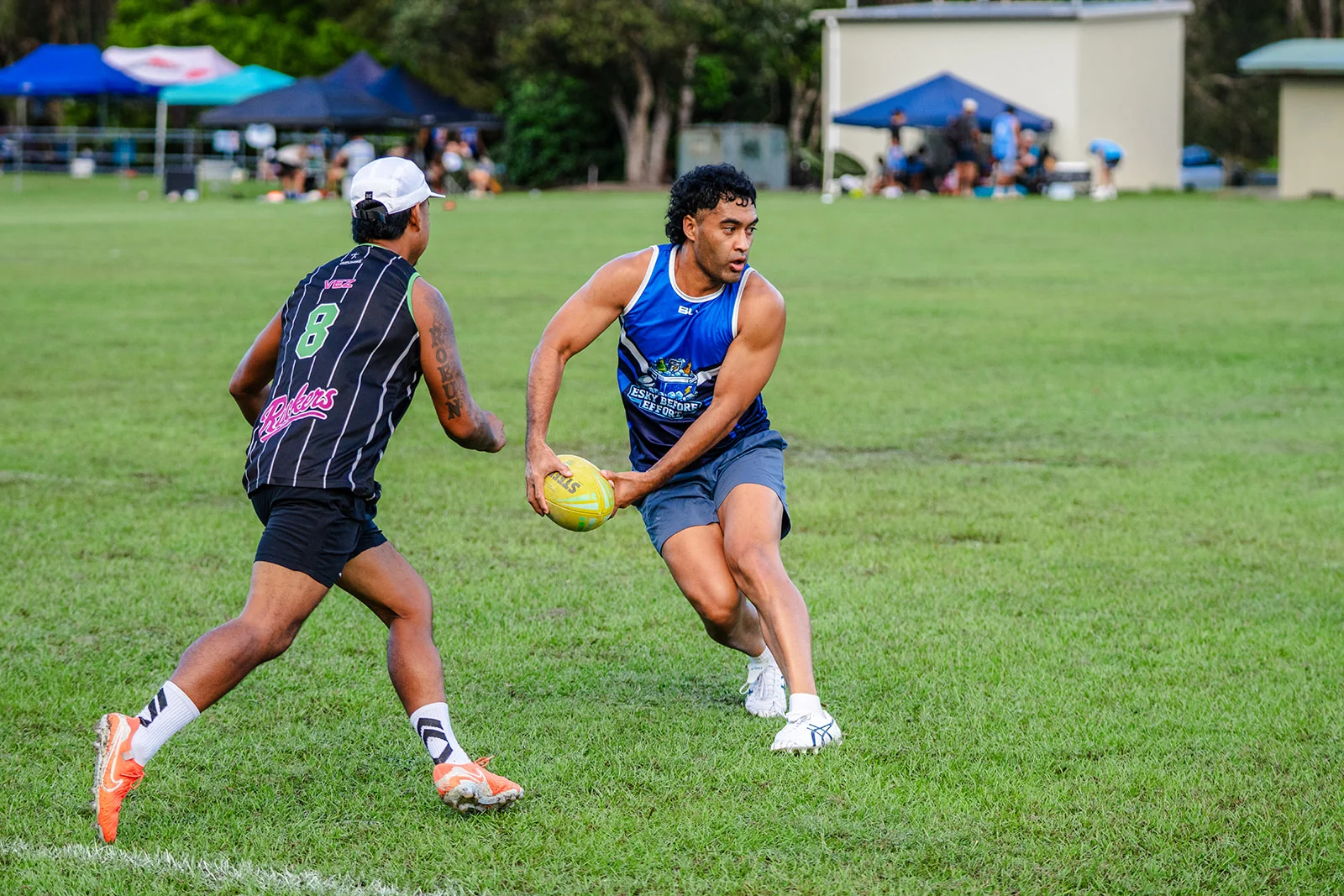 A ball carrier in blue turns toward a defender in black.