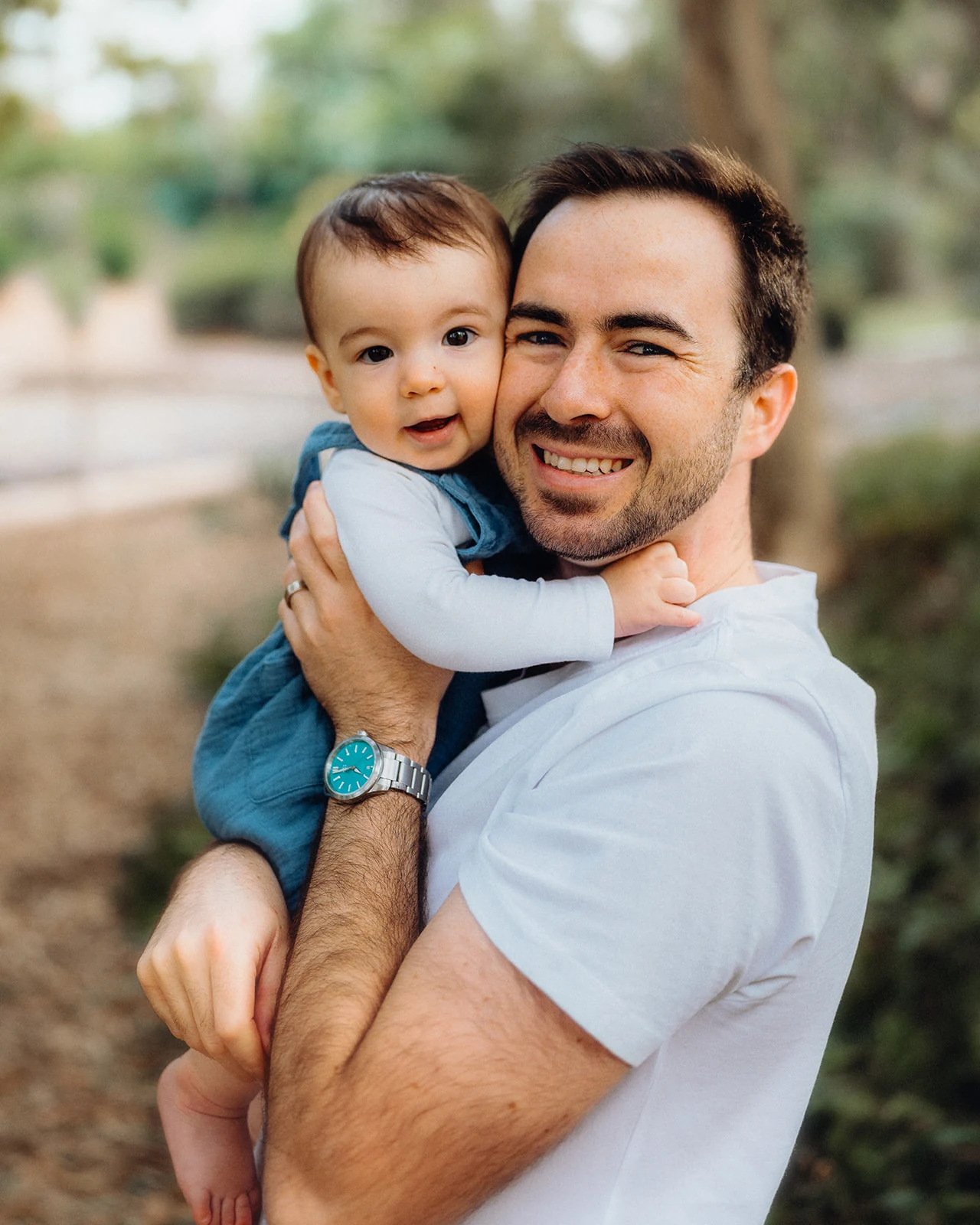 A father holds his smiling baby close to his face.