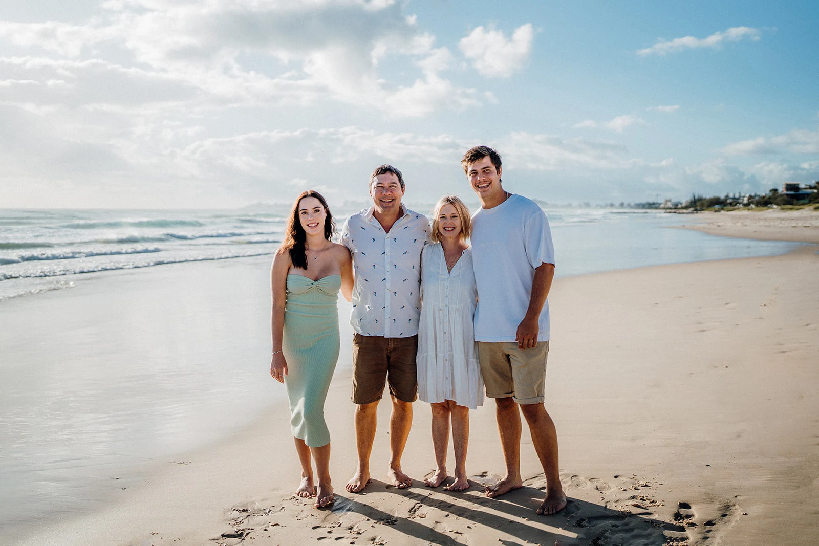 Four family members stand together beside the ocean.