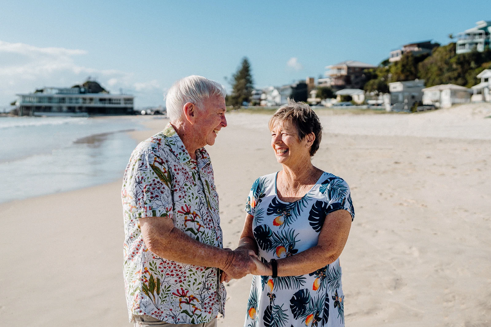 An older couple holds hands and laughs together.
