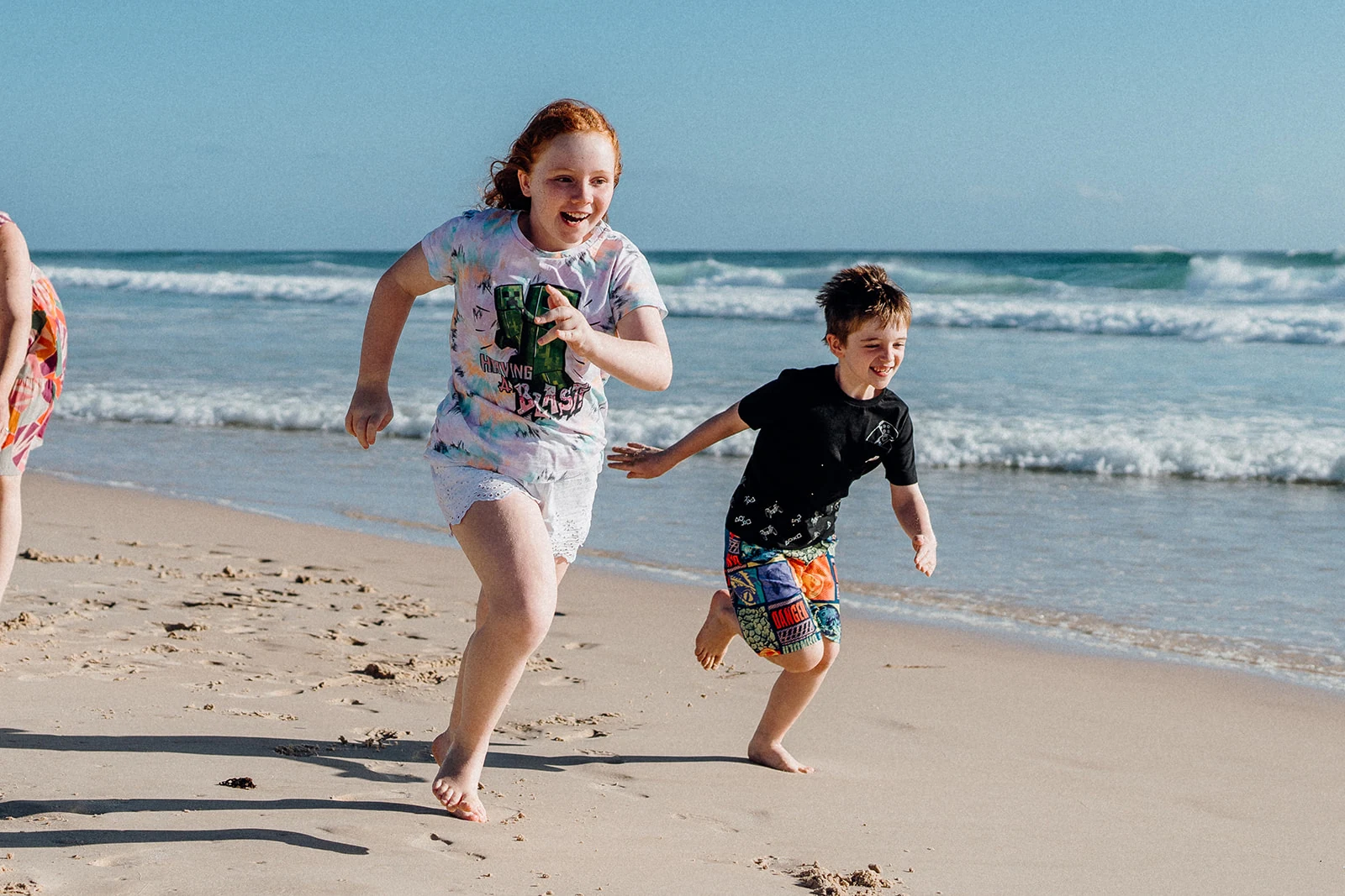 Two children run along the shoreline.