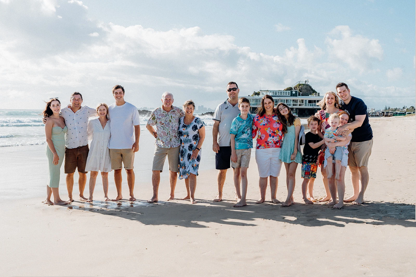 An extended family gathers for a portrait beside the sea.