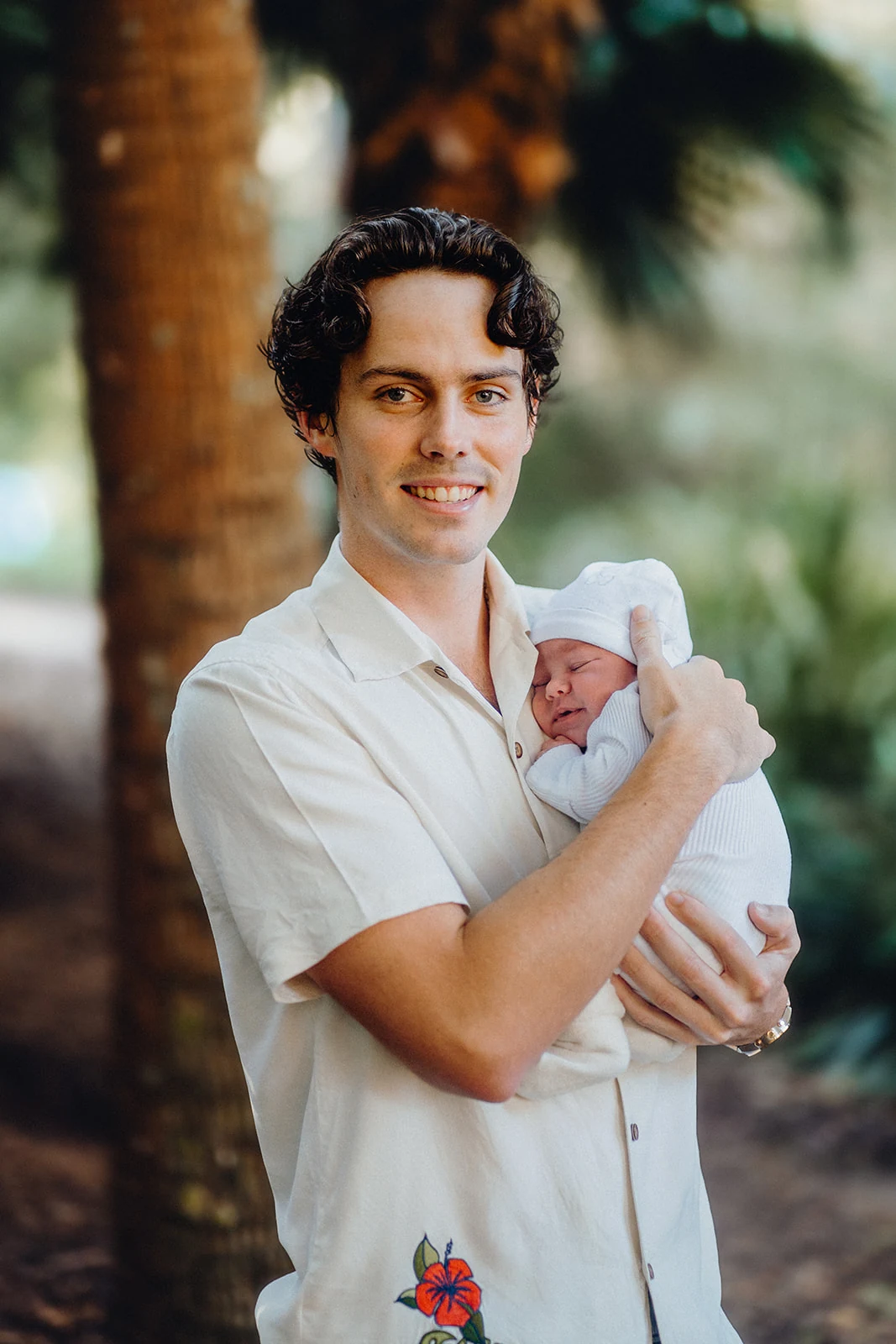 A father holds his newborn against his shoulder.
