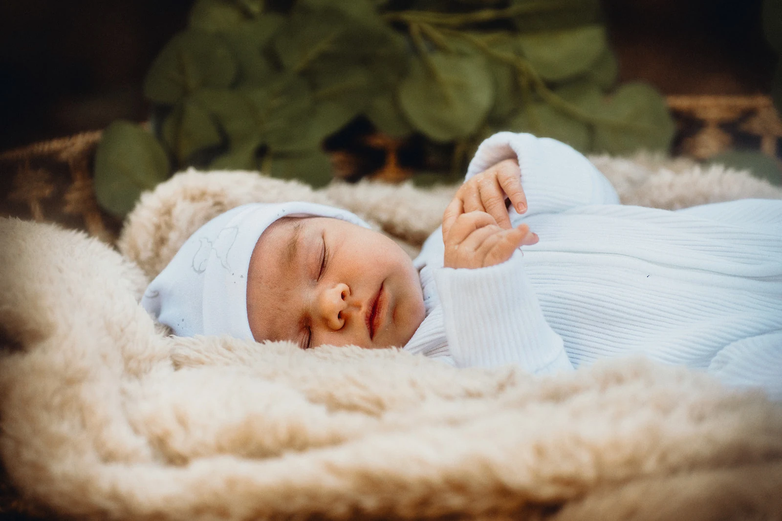 A sleeping newborn rests on a soft cream blanket.