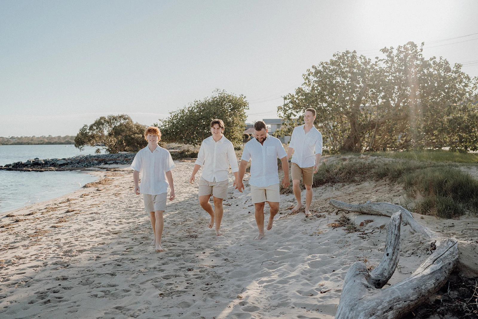 Four brothers walk along the beach in soft afternoon light.