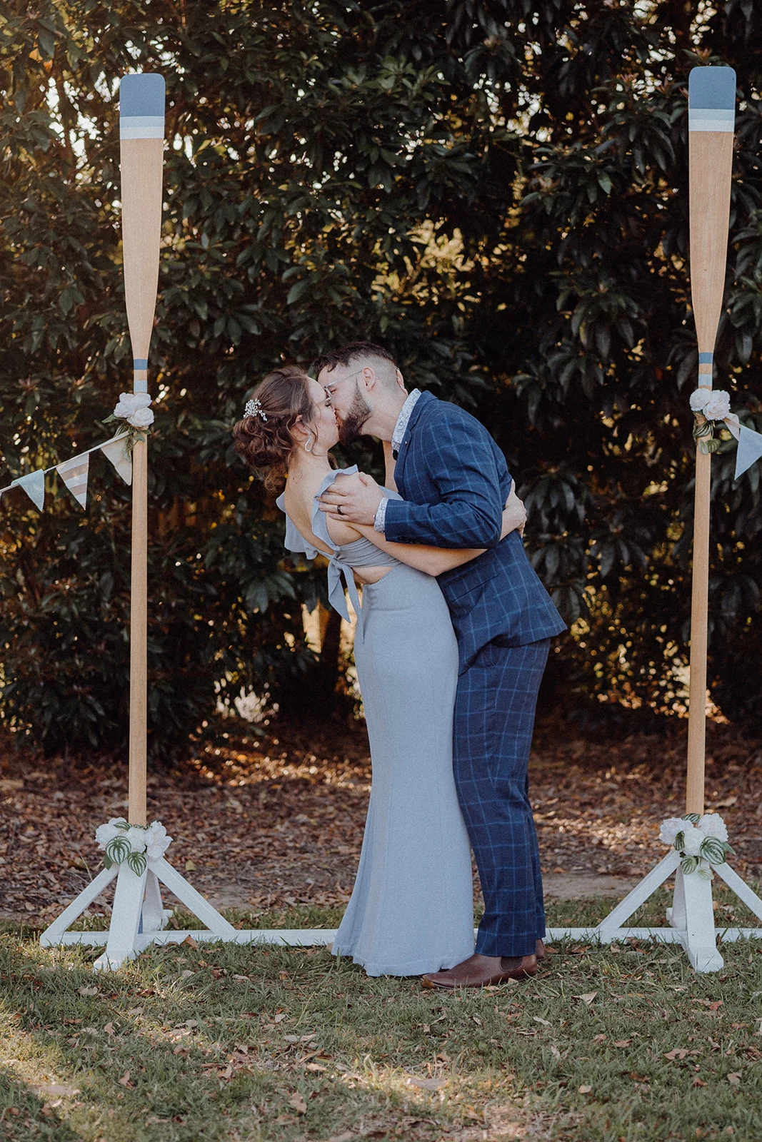 Newlyweds kiss between the posts of their garden ceremony arch.