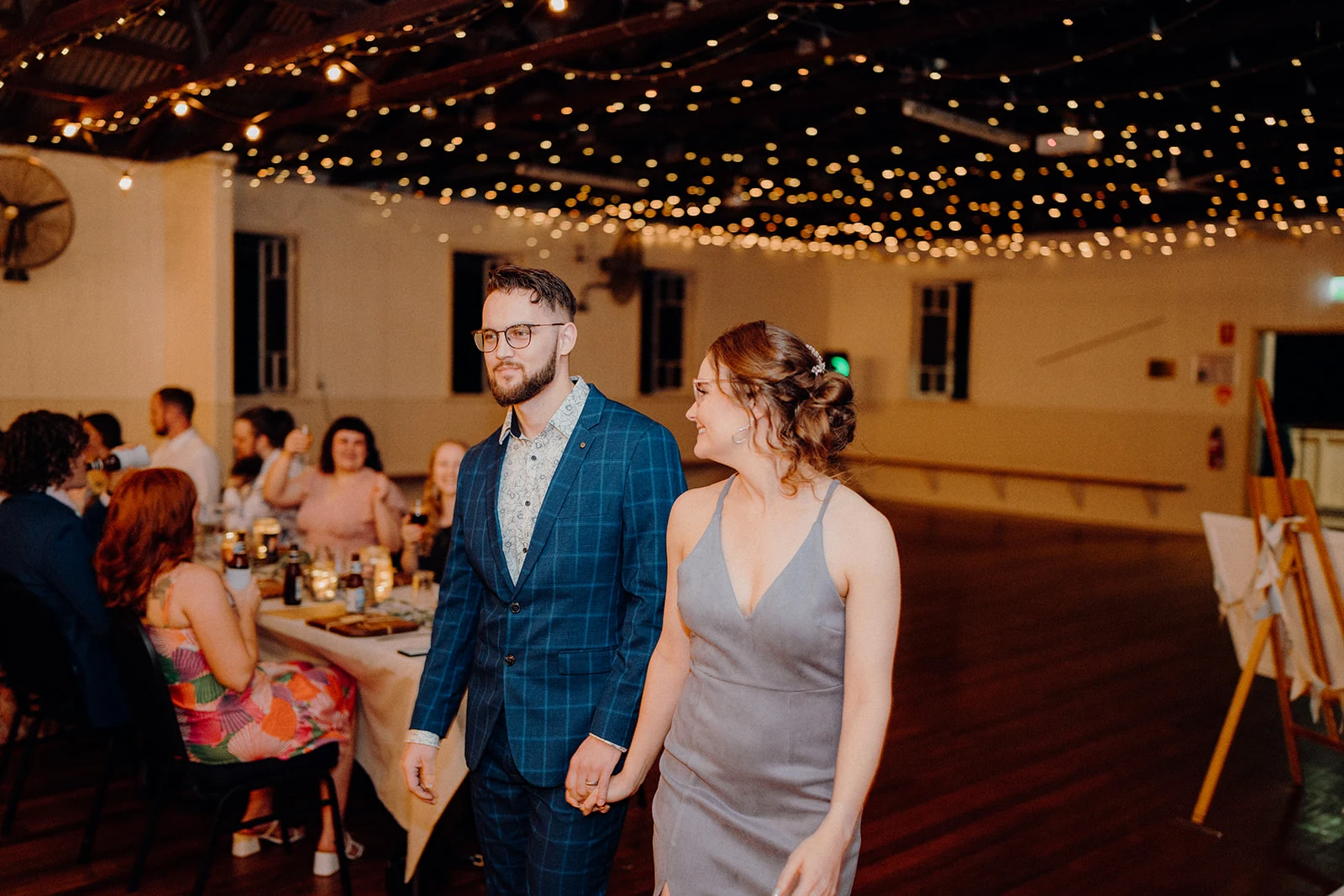 Newlyweds enter their reception beneath strings of warm lights.