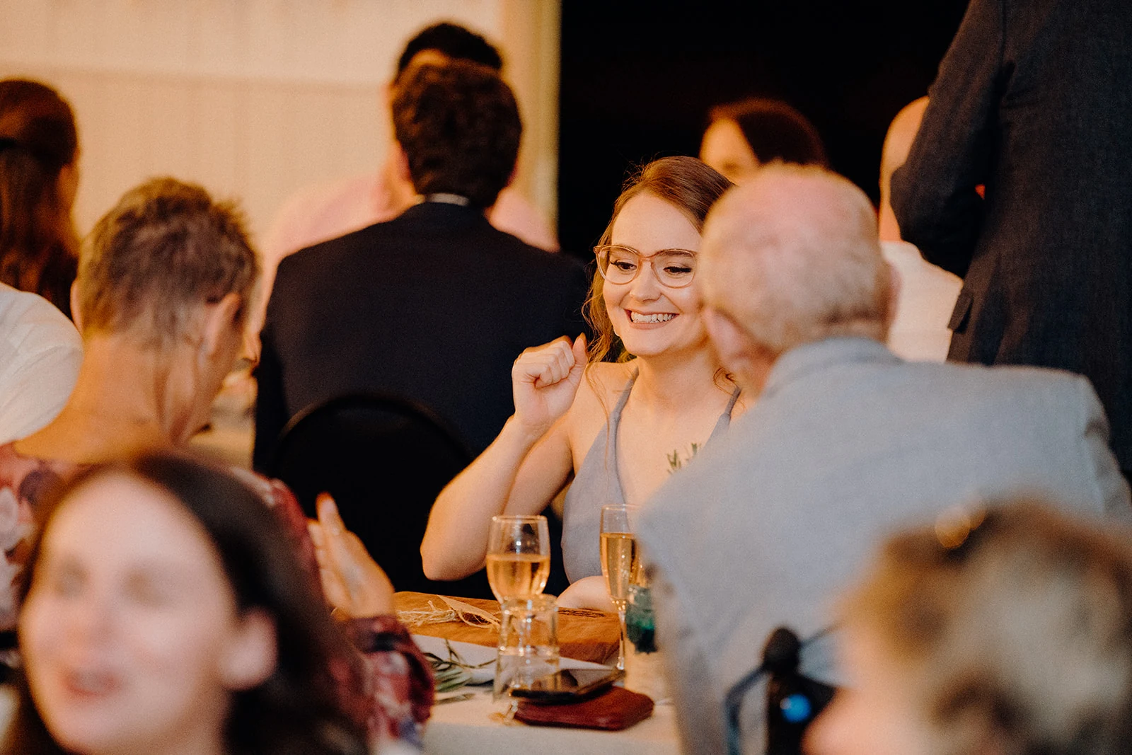 A bride smiles during conversation with guests at the reception.