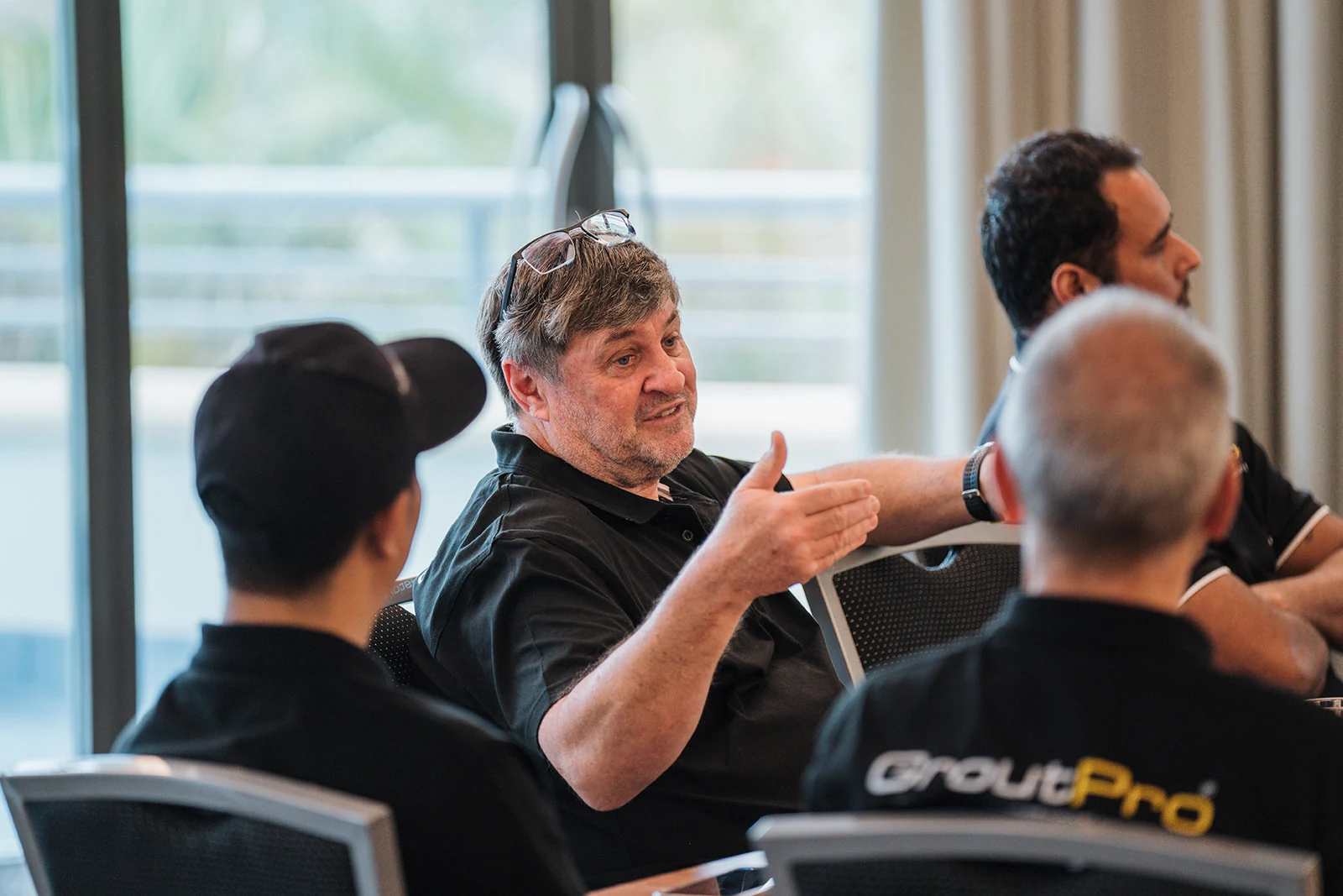 A man gestures while talking with colleagues around a conference table.