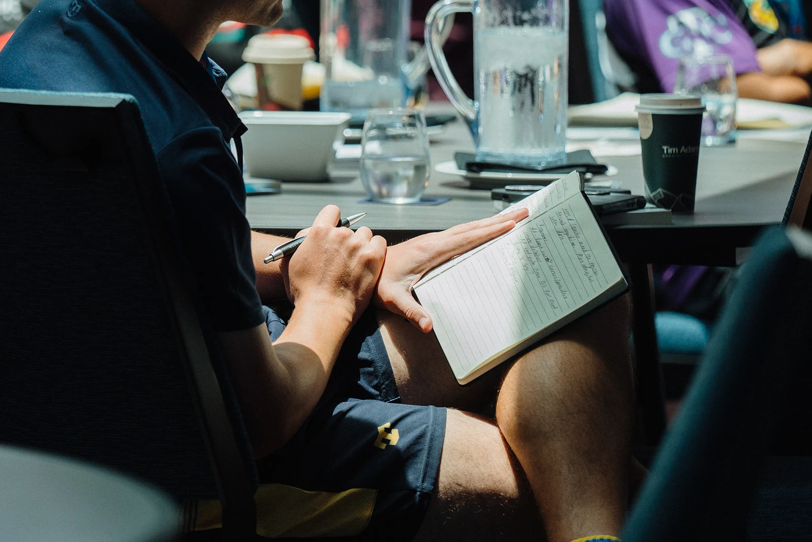 An attendee writes notes during a conference session.
